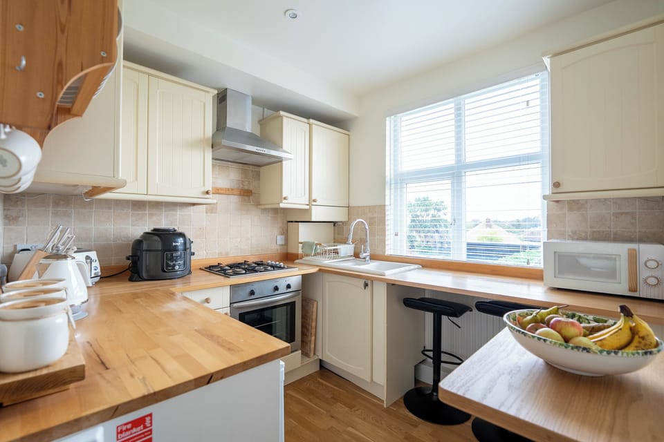 Bright, fully equipped kitchen with breakfast bar and garden views.