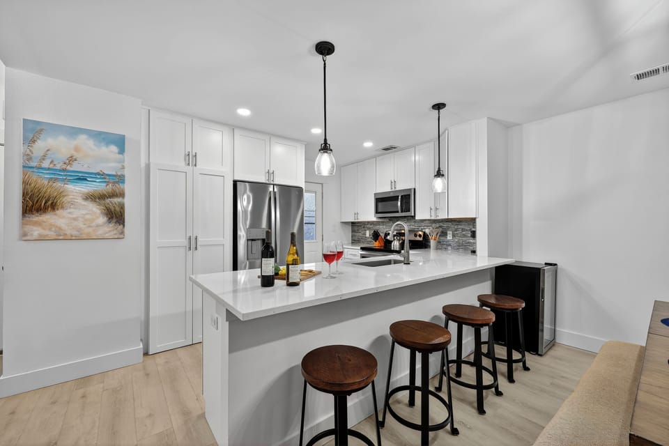 This modern kitchen is fully equipped with stainless steel appliances, ample countertop space, and additional mini fridge.
