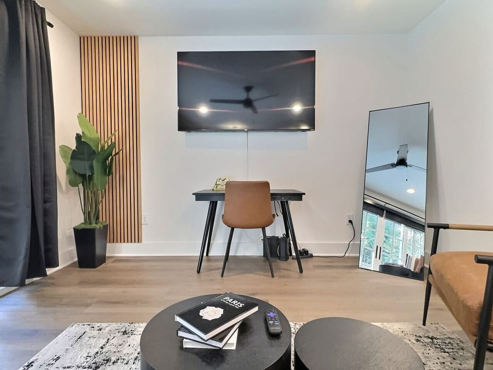 Bright and airy living area in this furnished apartment with comfortable seating, a TV, and a workspace, sleek window with city views, perfect for relaxing or staying productive.