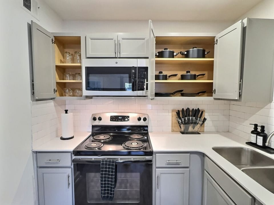 Modern kitchen with sleek stainless steel appliances and neatly arranged utensils, perfect for effortless cooking during your short-term rental stay.