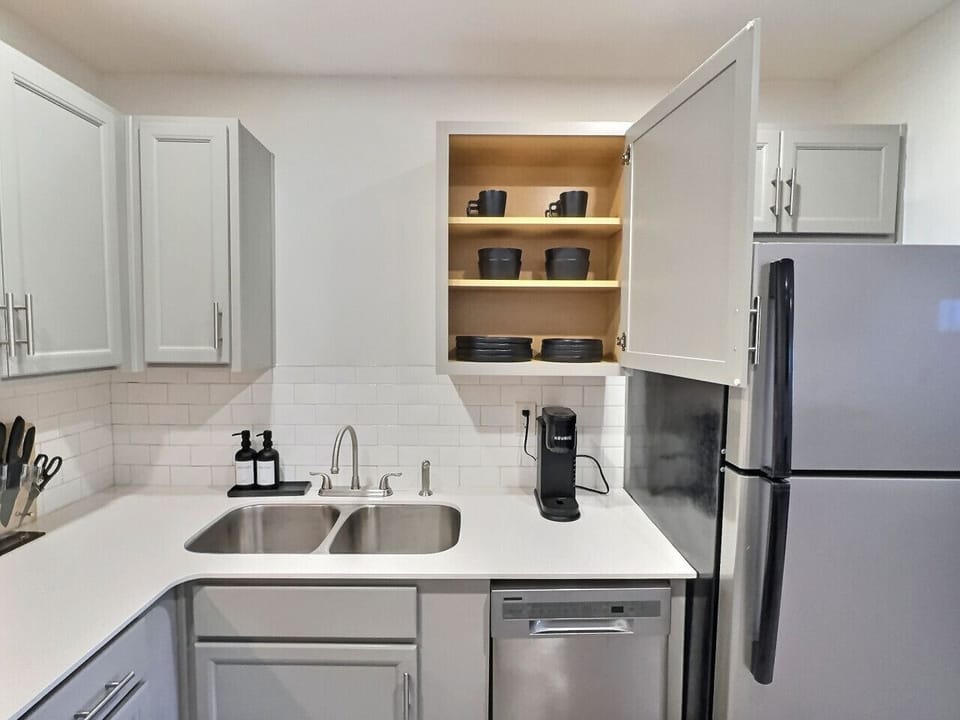 Modern kitchen with sleek stainless steel appliances and neatly arranged utensils, perfect for effortless cooking during your short-term rental stay.