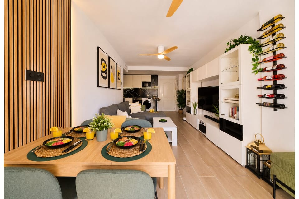 Stylish open-plan living room with a modern kitchen, smart TV, and natural light throughout — ideal for relaxing or sharing a glass of wine after a day by the beach.