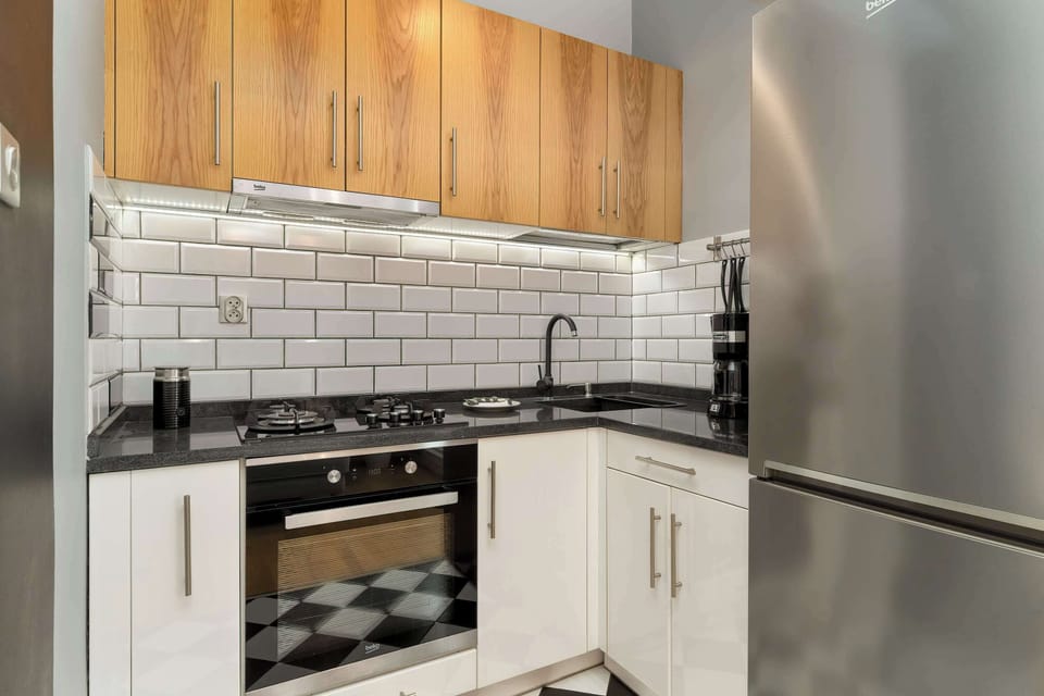 The modern kitchenette with wooden cabinets and white subway tiles provides everything needed for comfortable cooking.