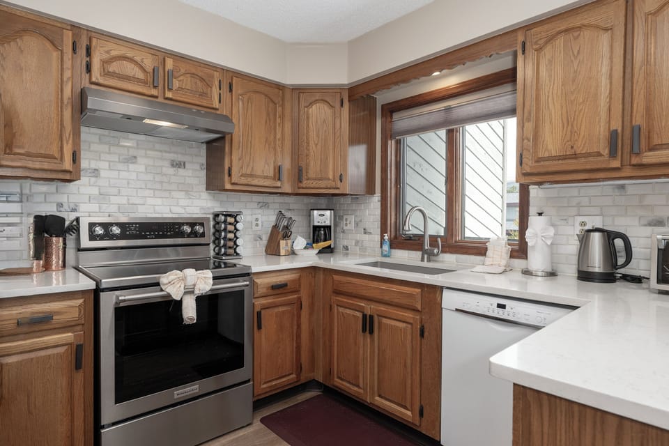 Step into your well-equipped kitchen featuring warm oak cabinetry, quartz counters, and everything you need for memorable meal prep.