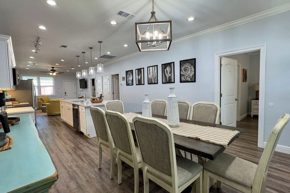 Open-concept kitchen and dining area with a long farmhouse table, modern lighting, and plenty of space for group meals.