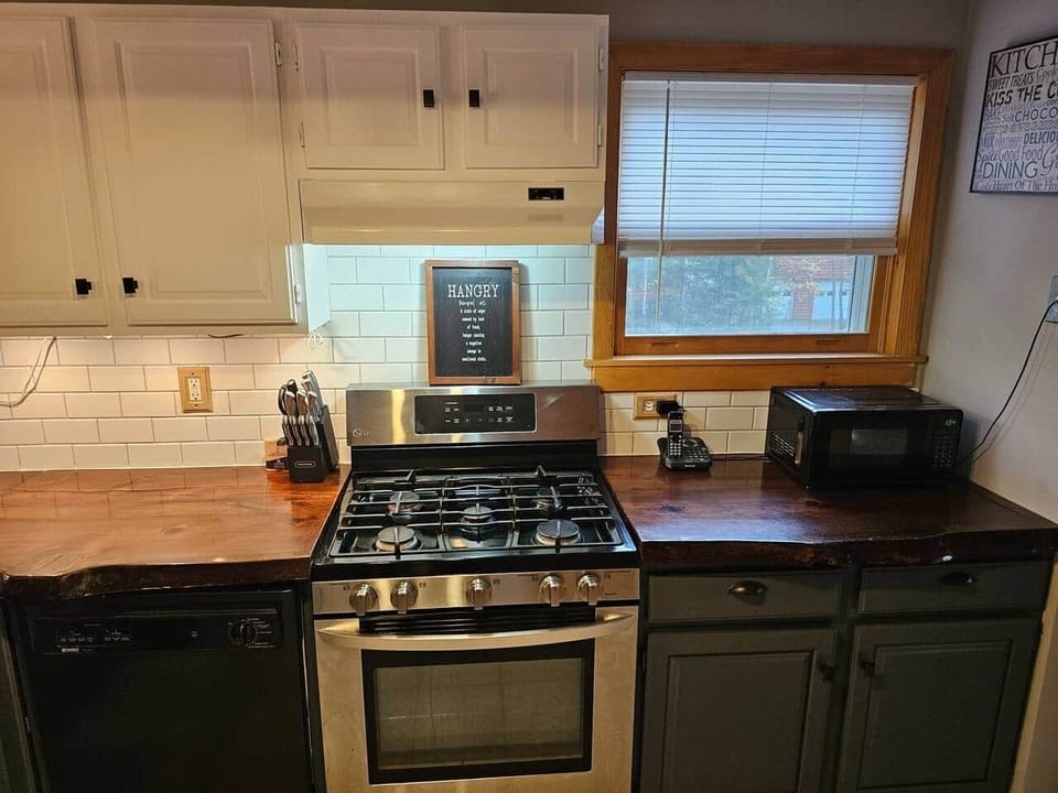 This kitchen blends style and function with a stainless steel gas range, wood countertops, and white subway tile. A microwave, dishwasher, and well-stocked essentials make it perfect for cooking meals during your mountain getaway.