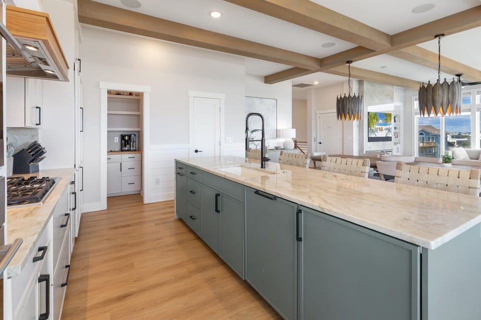 The fully equipped kitchen boasts a 6-burner stove, double ovens, large pantry, and sleek bar seating for four.