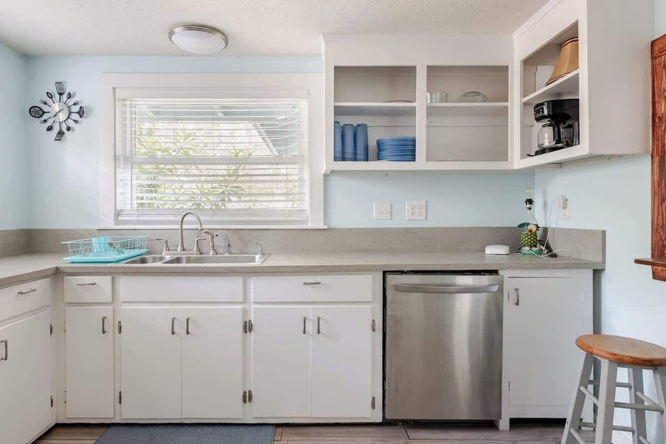 Bright and fully equipped kitchen with a full-size fridge, dishwasher, microwave, and electric range. Plenty of counter space, open shelving, and a convenient pass-through to the living room great for quick meals before heading out.