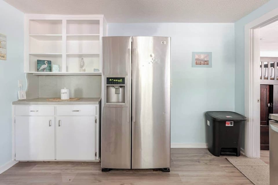 Bright and fully equipped kitchen with a full-size fridge, dishwasher, microwave, and electric range. Plenty of counter space, open shelving, and a convenient pass-through to the living room great for quick meals before heading out.
