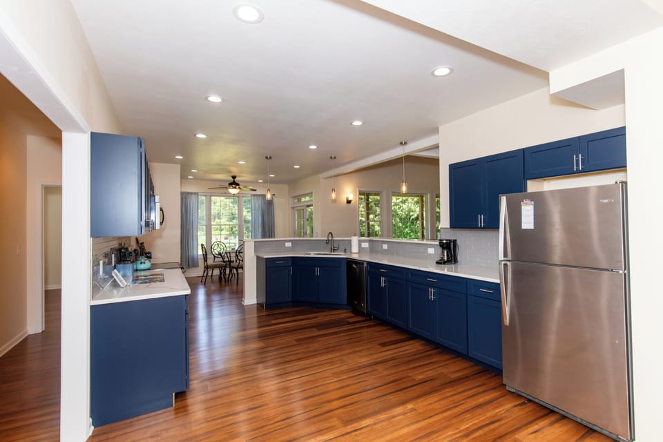 Step into your spacious gourmet kitchen with rich hardwood floors, modern navy cabinetry, stainless steel appliances, and abundant natural light—perfect for preparing memorable meals during your stay.