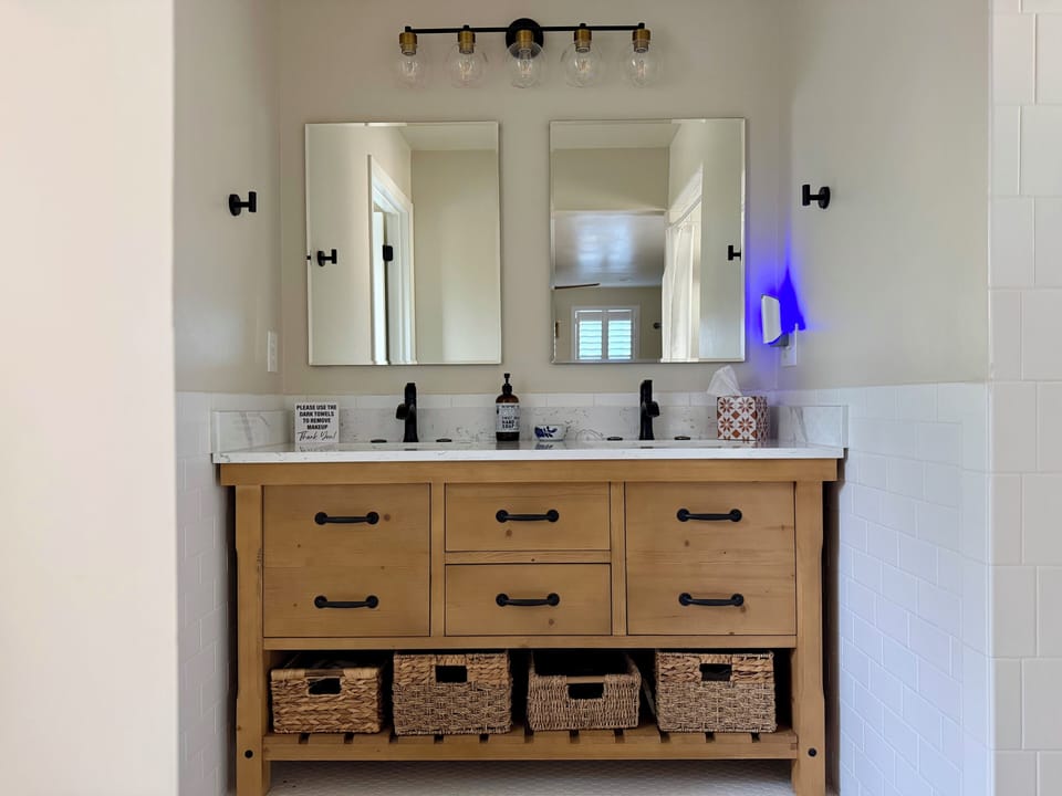 Double sinks with mirrors, water closet to left and shower to right.