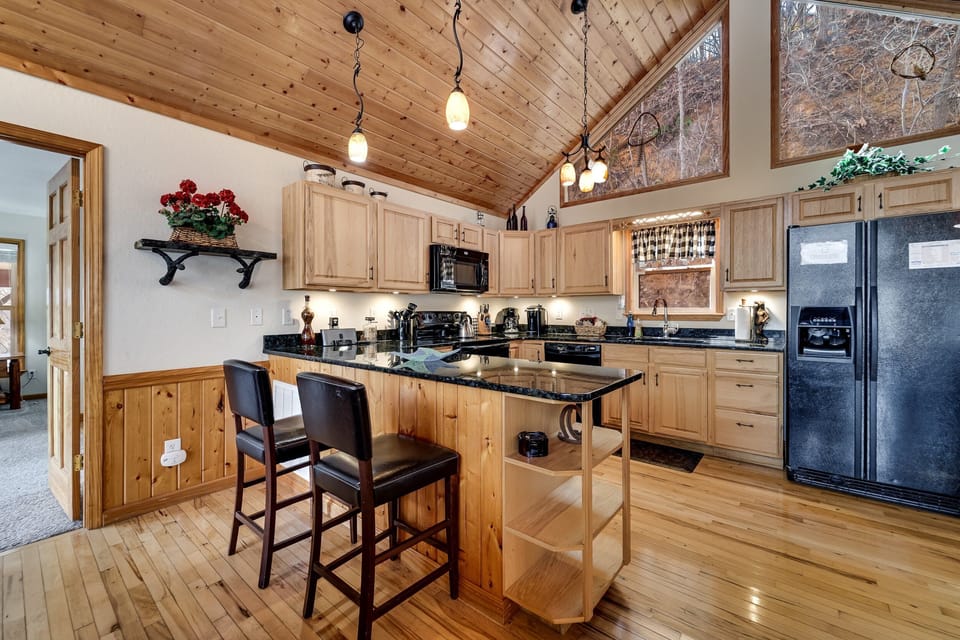 Dining area with round table and view into the fully equipped kitchen at Dream Weaver cabin in Bryson City.