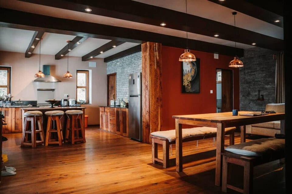 Open-plan kitchen and dining area with rustic wooden beams and natural light.