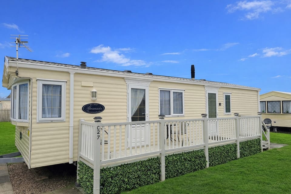 Exterior – Spacious static caravan featuring private veranda, outdoor seating and open green space. Ideal for comfortable seaside stays and family getaways.