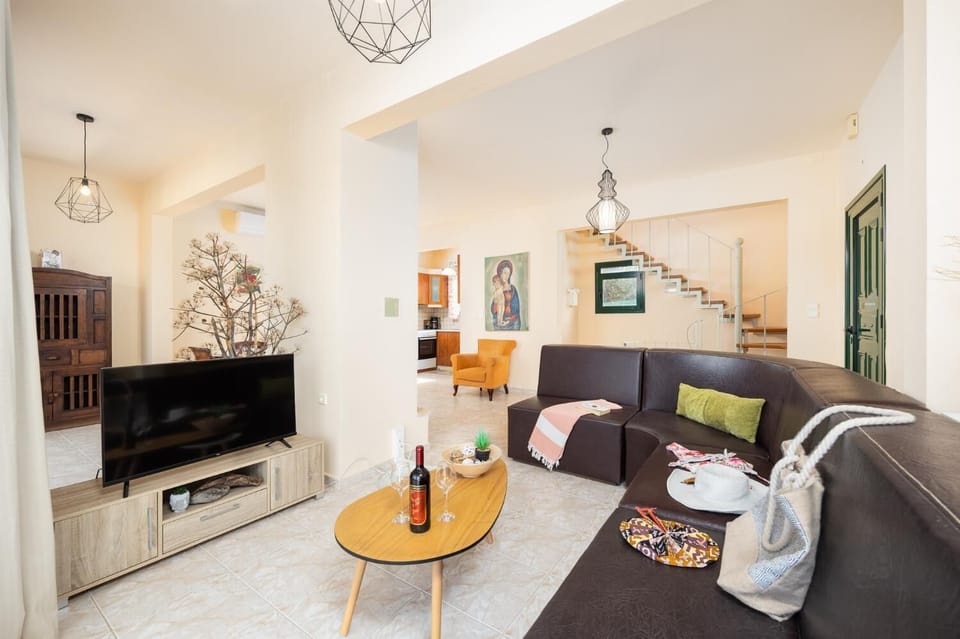 Open-plan living room with sofa, dining area, kitchen, ornamental fireplace, A/C, WiFi internet, and satellite TV