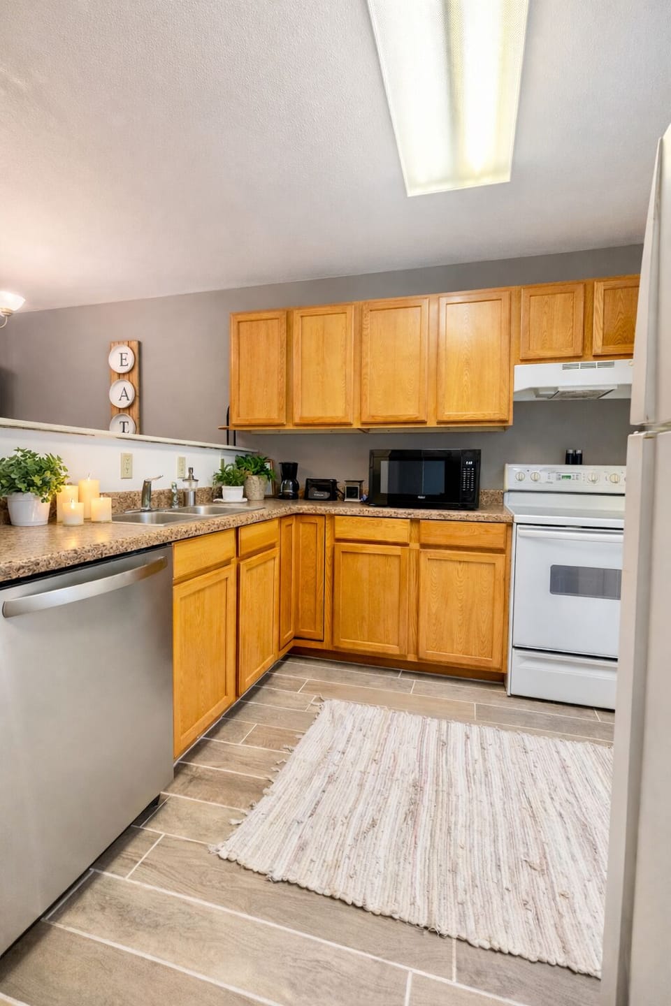 Bright, cozy kitchen w/warm wood cabinets, white appliances, & place to unwind.