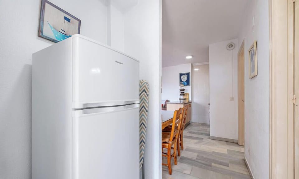 A room with a refrigerator and a dining table. A simple space room.