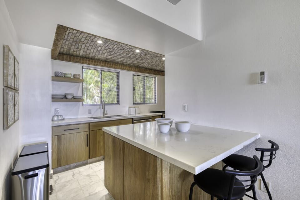 The updated kitchen features a breakfast bar with seating and a unique brick-arched ceiling.