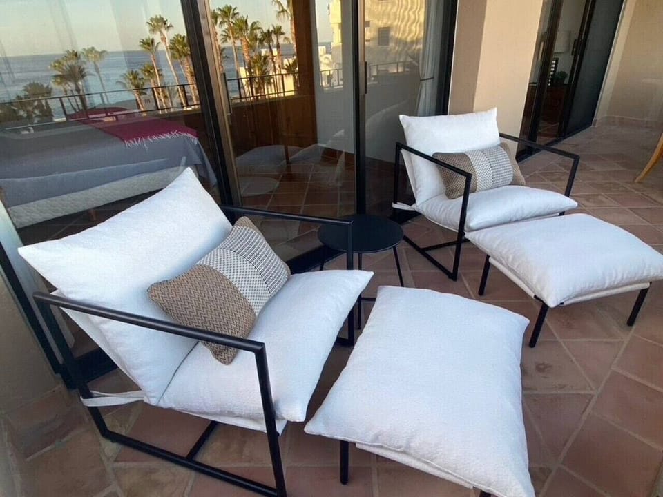 Cozy balcony with two chairs and a small table.`