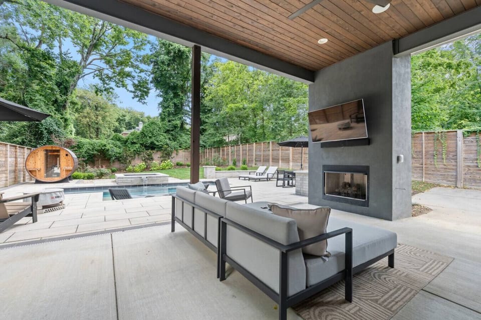 Large outdoor covered patio features a spacious seating area, dining table, high-end BBQ grill, mini fridge, and a smart TV—perfect for relaxing, entertaining, and enjoying meals in comfort and style. Please note the fireplace is not available.