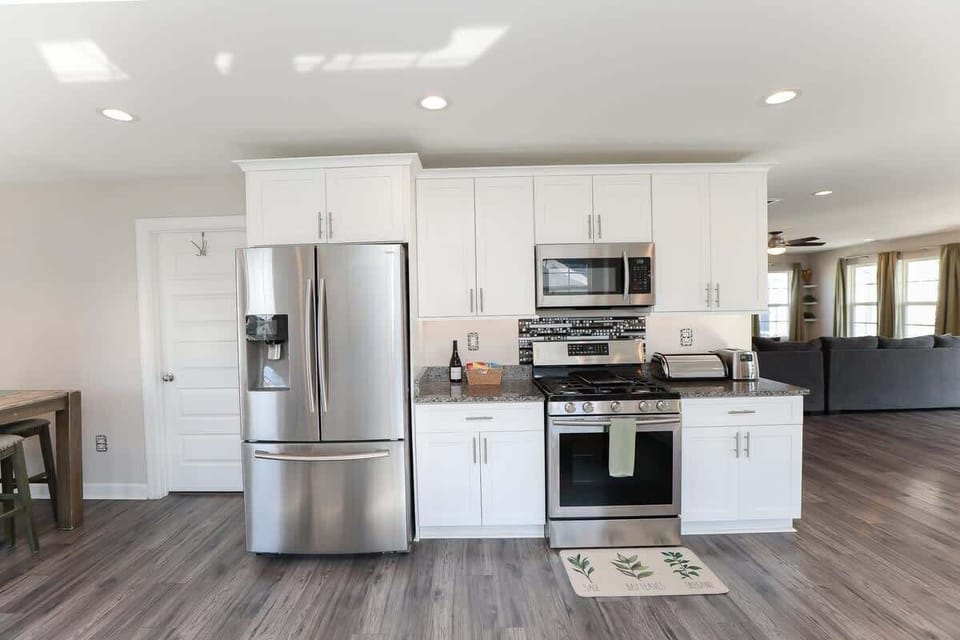 Kitchen with refrigerator, oven, stove, microwave, toaster, seating, additional storage and view of the living room. 
