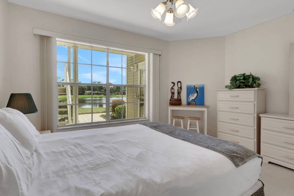The guest bedroom has a queen bed and a partial view of the lake behind the condo.