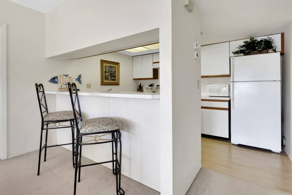 A pass-through eating bar with a pair of barstools divides the kitchen from the main living space.