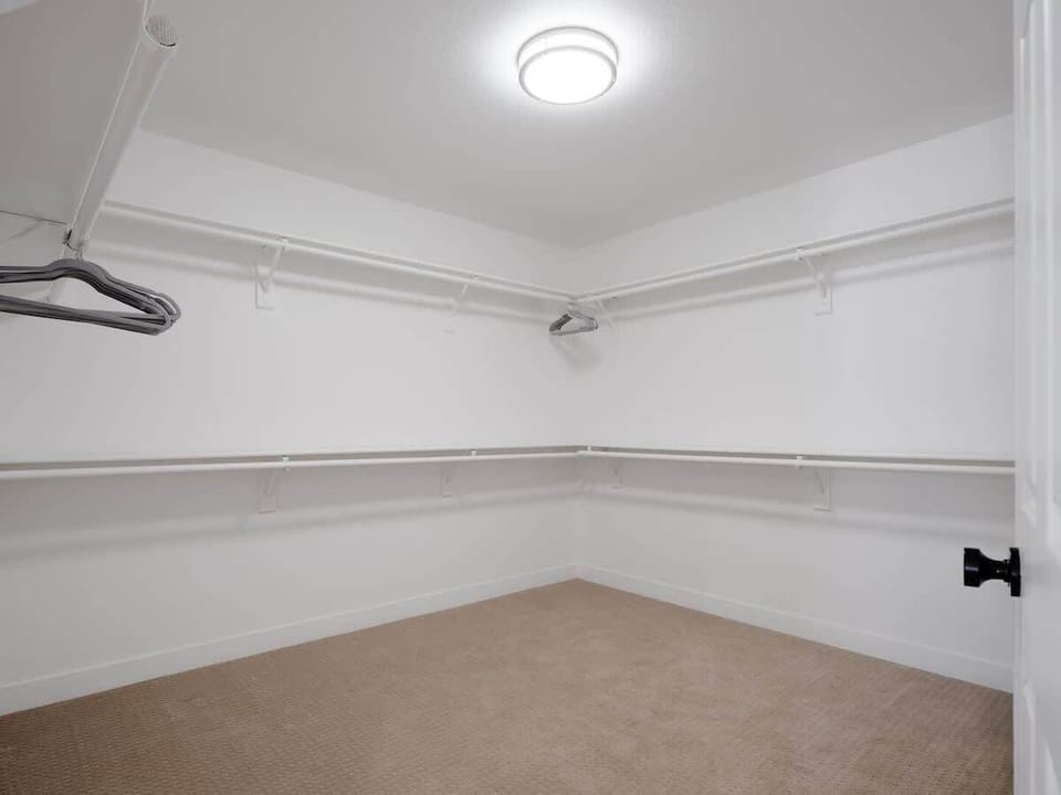 Primary bedroom with a King bed, smart TV, office desk with chairs, large walk-in closet, and en-suite bathroom with private access to the outdoor patio. (1st Floor)