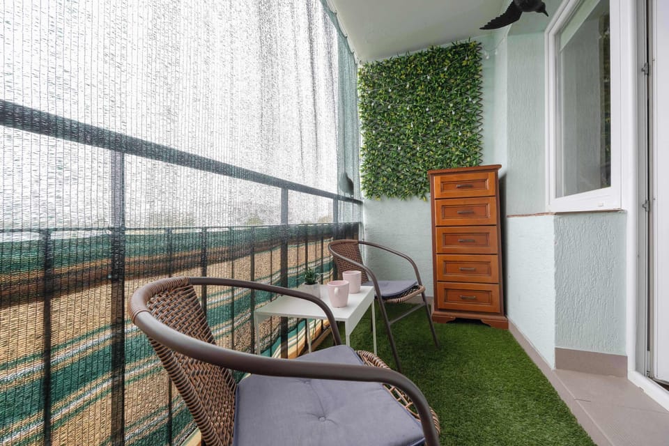 A balcony with artificial grass flooring, wooden panels, and a compact storage cabinet.