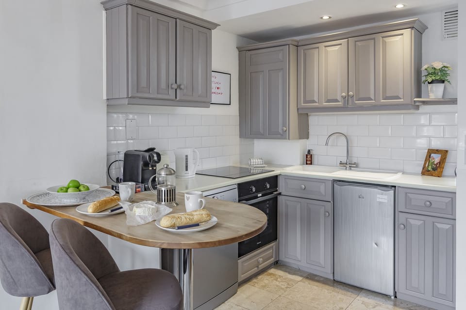Fully equipped kitchen with grey cabinets, hob and oven.