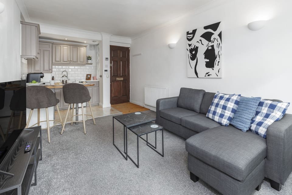 Modern lounge with sofa, coffee tables, and wall art.