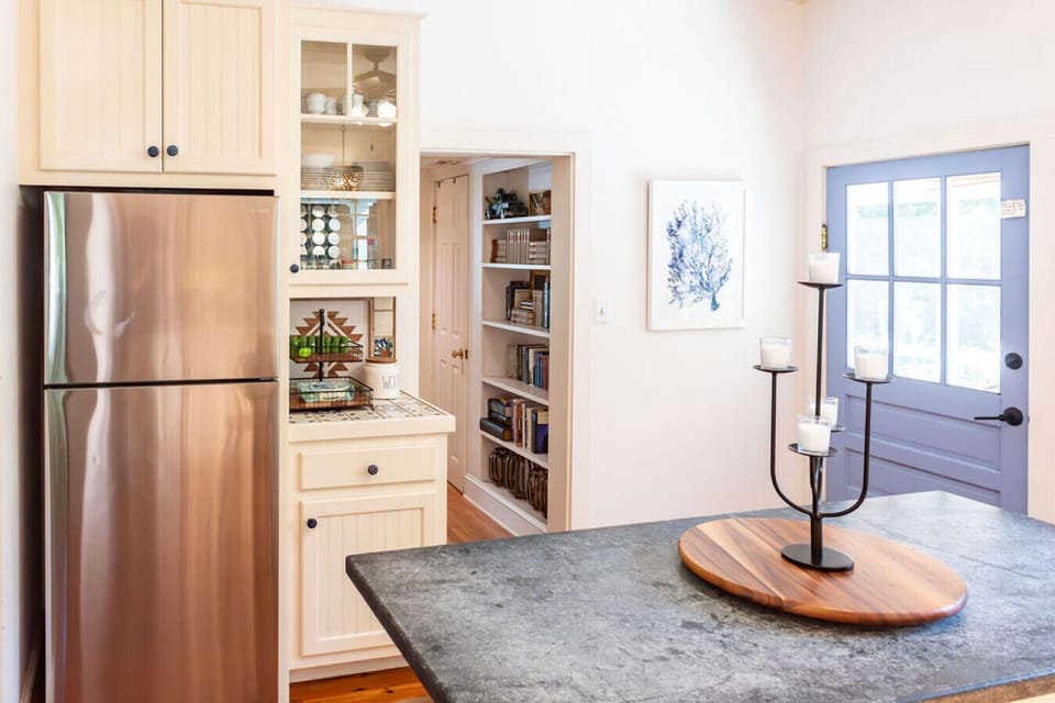 Well-equipped kitchen with ample storage, stainless steel fridge, and open pantry access