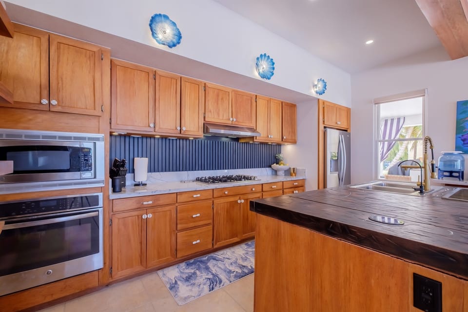 The fully equipped kitchen features custom wood cabinetry, modern appliances, and a spacious island with prep space and seating. Thoughtful layout and ample storage make cooking and entertaining easy and enjoyable.
