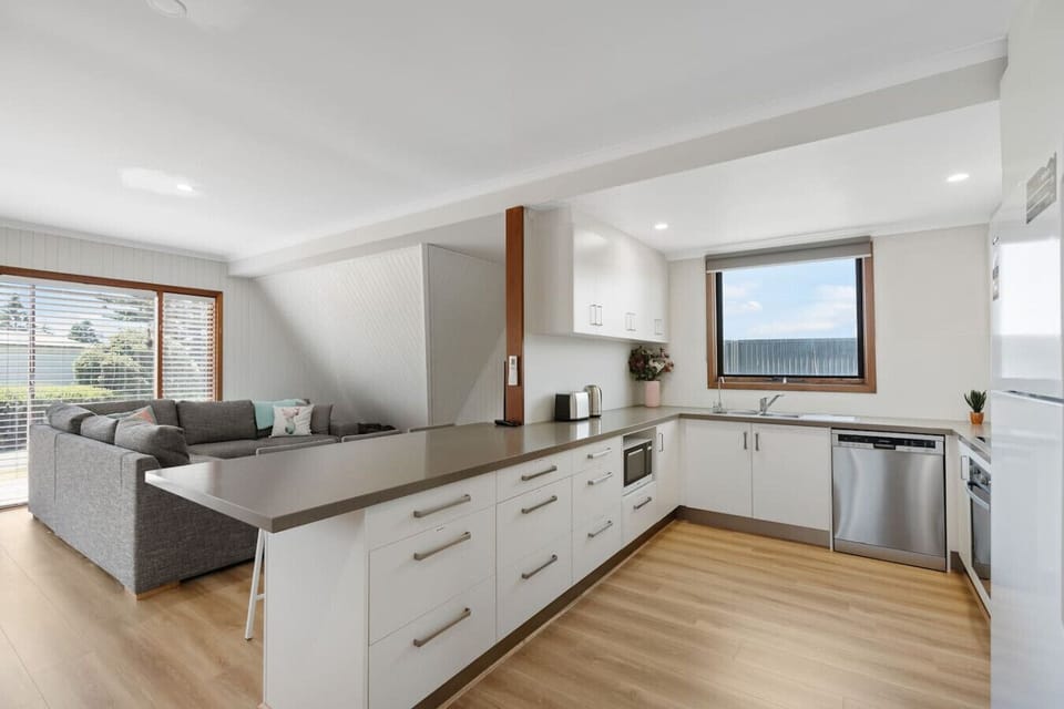 A sleek, fully equipped kitchen with stainless-steel appliances, a Nespresso machine, a dishwasher, and generous bench space makes preparing meals as effortless as the seaside lifestyle.