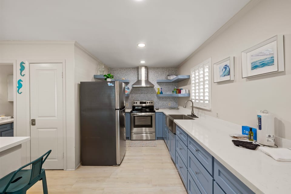Modern kitchen with stainless steel appliances and ocean-blue cabinetry.