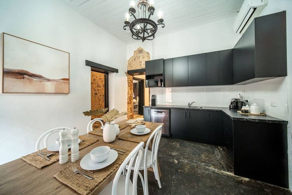 A bold black kitchen meets rustic charm, complete with a farmhouse dining table set for an inviting meal.