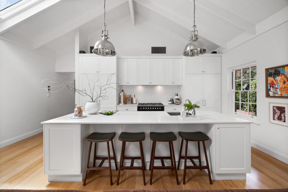 The kitchen island with its cushioned stools creates a welcoming spot for relaxed breakfasts or conversation while meals come together.