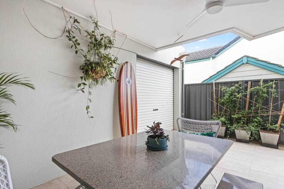 Enjoy relaxed outdoor meals on the covered patio where a stone table, greenery and coastal touches create an easy alfresco setting.