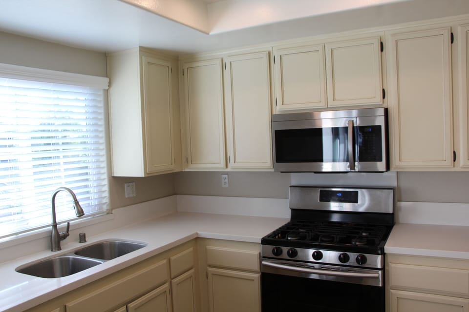 Kitchen with gas stove oven, microwave, stainless steel sink, decorative cabinet