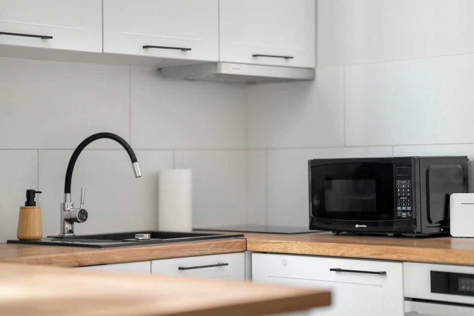 The modern kitchen with black accents and a wooden countertop offers both comfort and style while cooking.