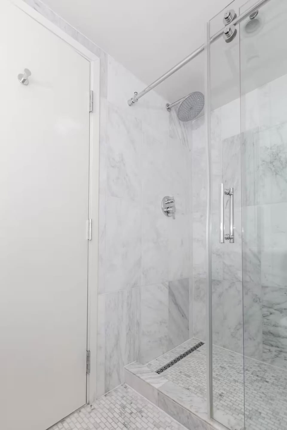 Rinse off under a modern rainfall shower in marble surroundings.