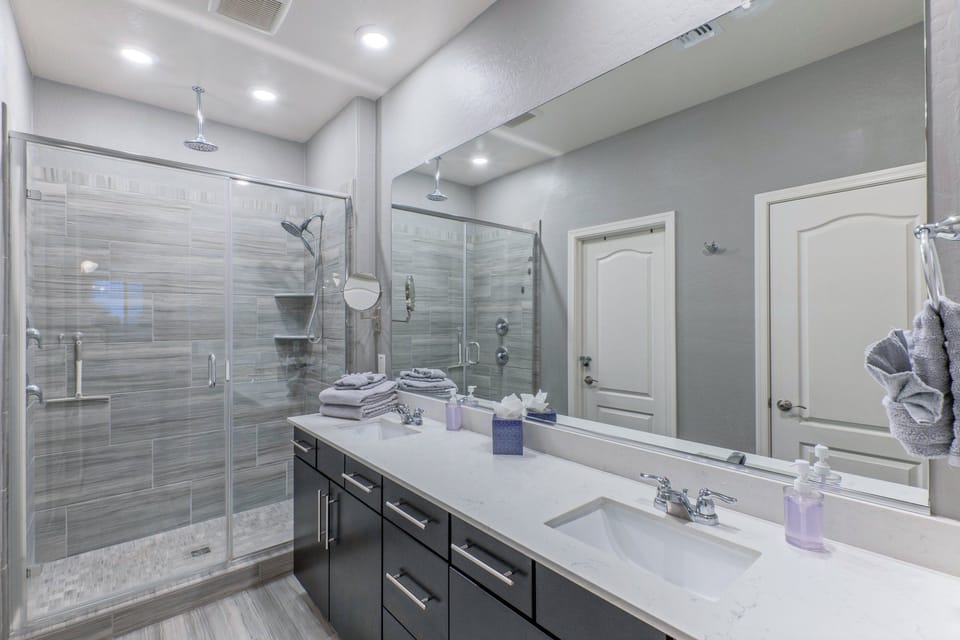 Primary suite's bath has dual vanity sinks and a tiled walk-in shower.