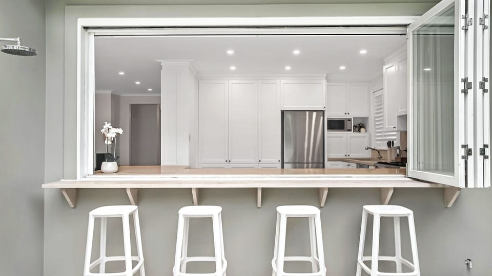 Kitchen servery window opening to outdoor bar seating
