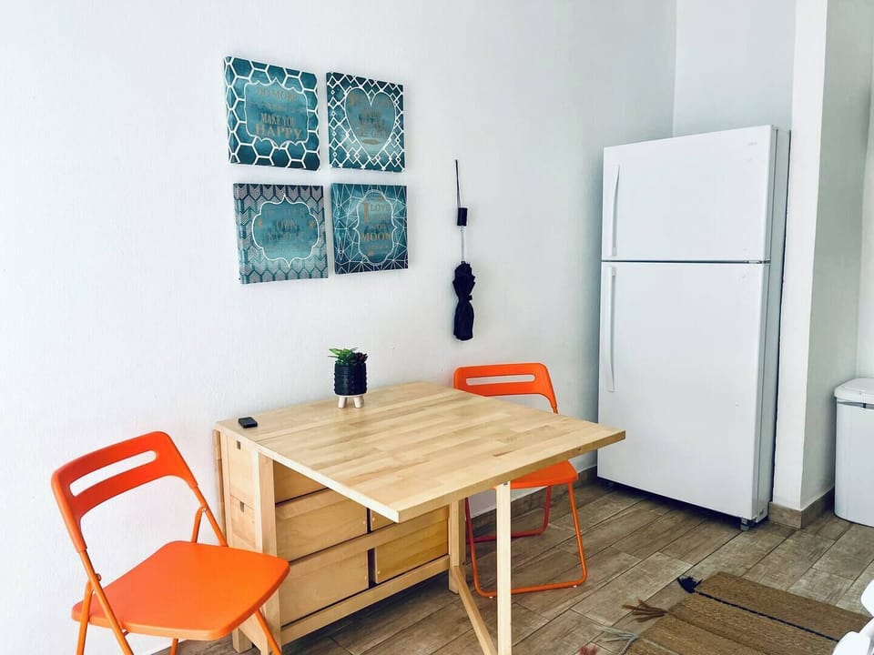 Savor your meals in our charming kitchen area, featuring a convenient fridge, a stylish dining table, and tasteful wall art to enhance your culinary experience.