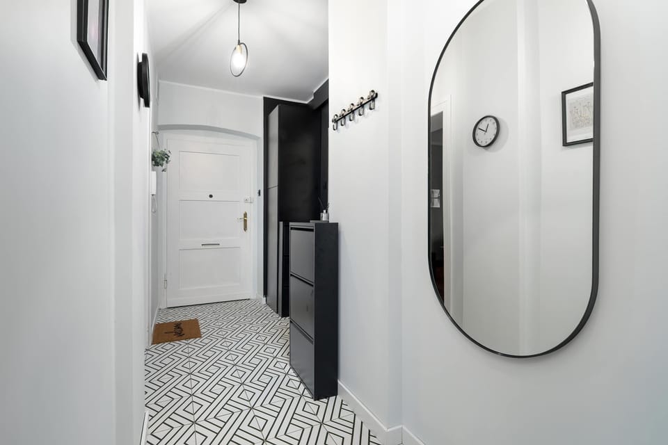 A modern hallway or entrance area with a round mirror on the wall. The flooring has a geometric pattern, giving the space a stylish touch.