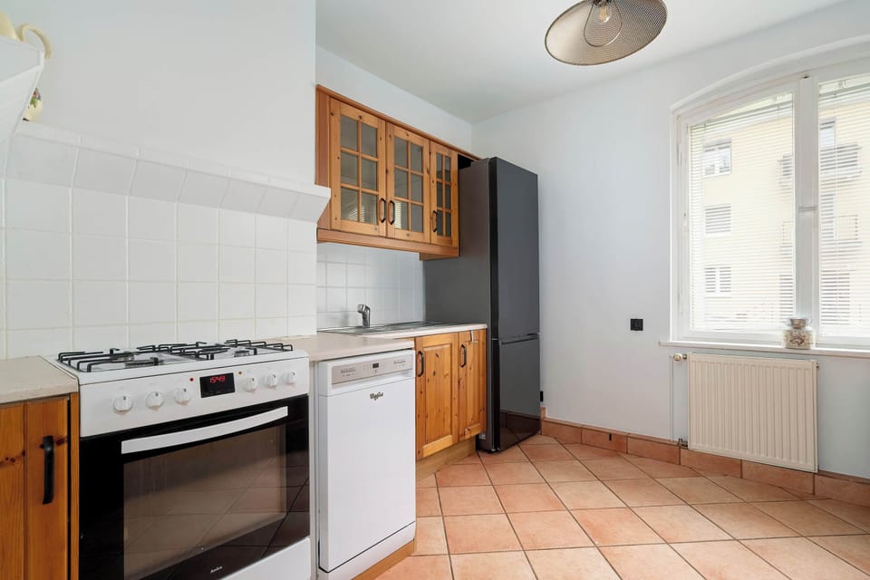 Another angle of the kitchen, showing the oven, gas hob, and cabinets. The layout is functional with natural lighting from the window.