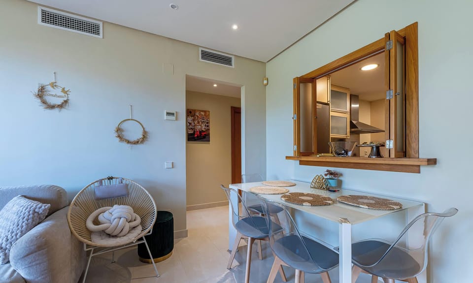 Stylish interior with a blend of textures and neutral tones. Features a comfortable sofa, unique chair, and a view into the kitchen. interior design homestyle.