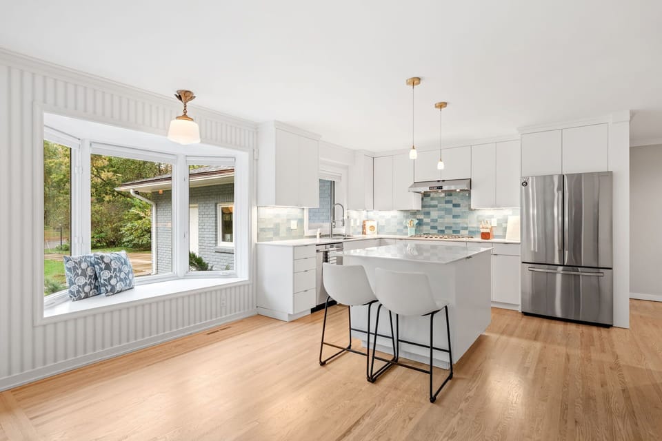 You'll love cooking in this bright, modern kitchen with its sleek island, pendant lights, and cozy window seat overlooking the garden.