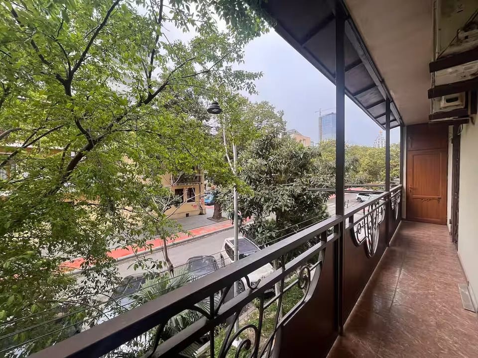 Large balcony overlooking a peaceful street with trees nearby.