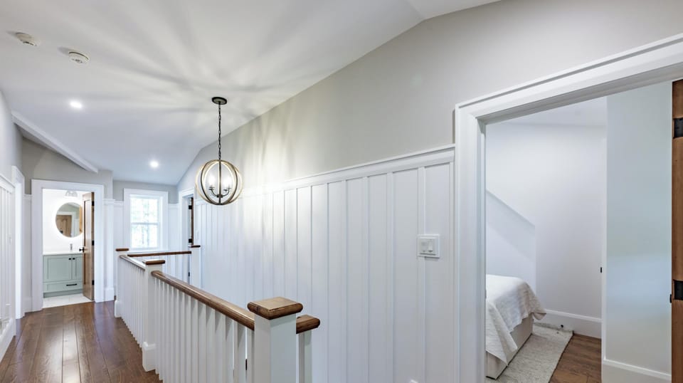 Bright upstairs hallway with charming wainscoting and hardwood floors